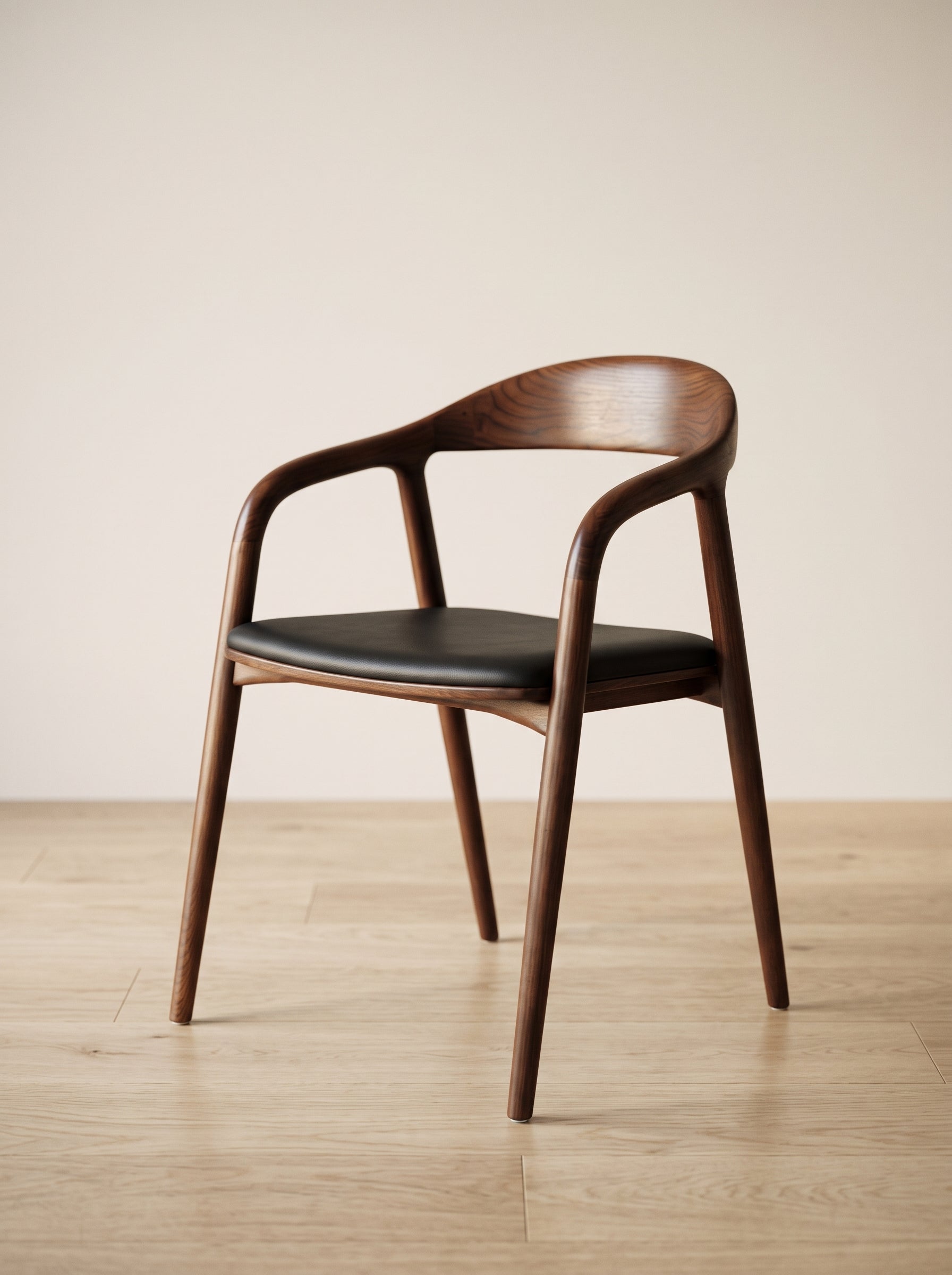 A mid-century modern wooden dining chair with a curved backrest, armrests, and a black upholstered seat, shown on a light wood floor against a neutral beige wall.