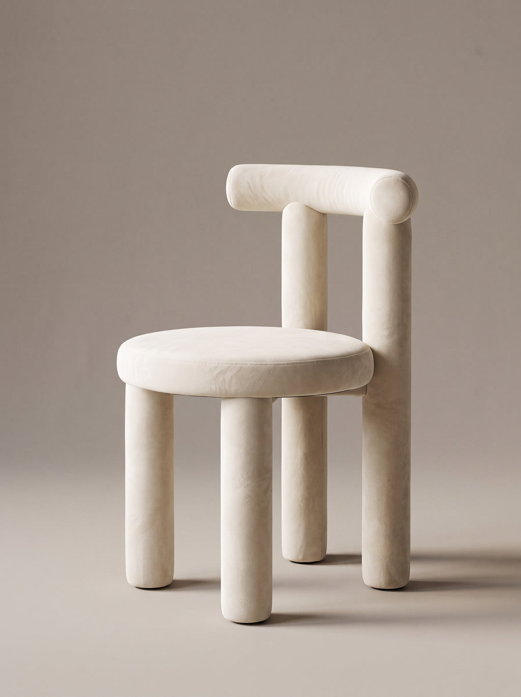 A minimalist, sculptural stool with a rounded, cushioned seat and thick cylindrical legs, upholstered in a warm off-white fabric, set against a solid taupe background.