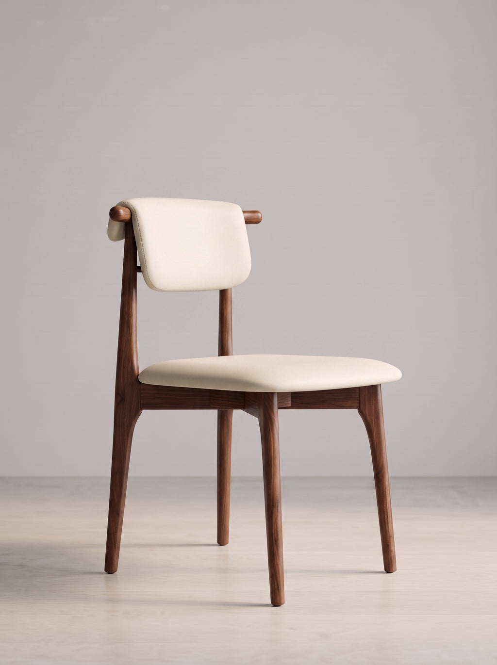 A mid-century modern dining chair with a warm brown wooden frame and cream-colored upholstered seat and backrest, set against a minimalist light gray studio background.
