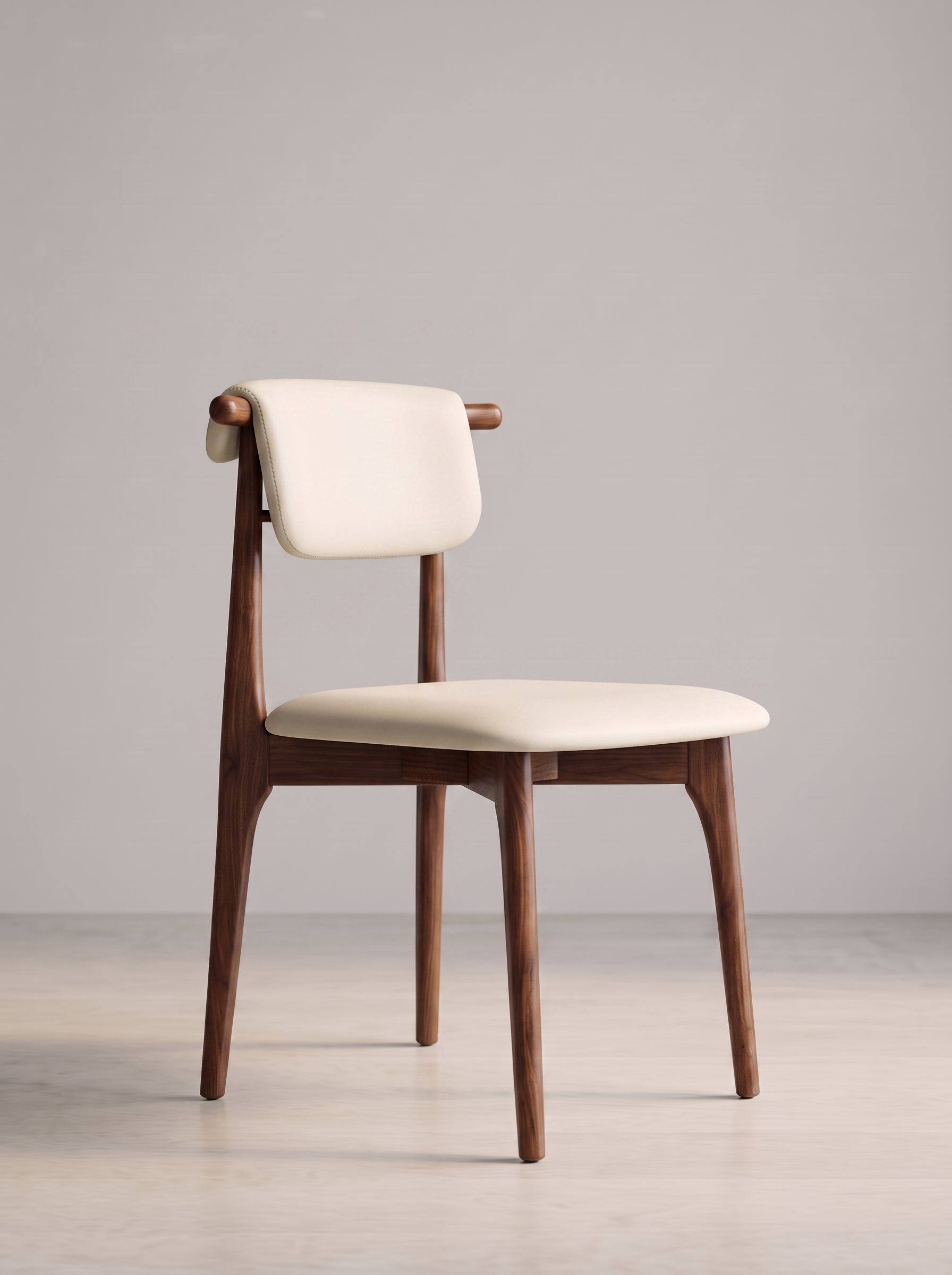 A mid-century modern dining chair with a warm brown wooden frame and cream-colored upholstered seat and backrest, set against a minimalist light gray studio background.